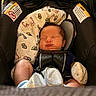 baby, blanket, car_seat, child, closeup, clothing, comfort, cute, face, head, indoors, infant, mitten, newborn, peaceful, resting, safety_harness, sleeping, sock, soft_lighting