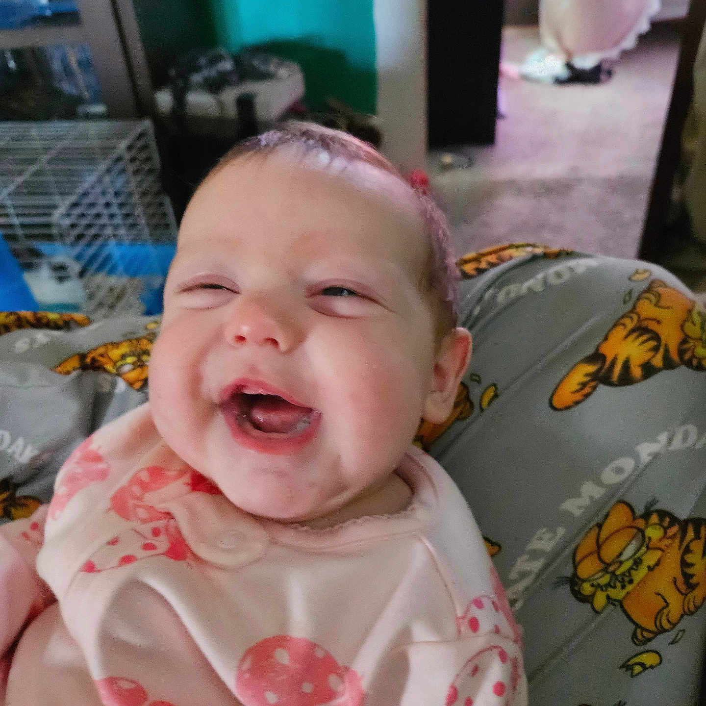 Winters is registered to the contest to win money with this photo: baby, cage, carpet, casual, child, cute, expression, face, furniture, garfield, happy, home, human, indoor, infant, person_holding, pink_clothing, polka_dots, portrait, smiling