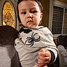 Sebastian is registered to the contest to win money with this photo: toddler, child, baby, indoors, person, clothing, spider_design, mustache_drawing, hand, face, window, door, adult_hand, portrait, cute, expression, black_hair, long_sleeve, home, holding