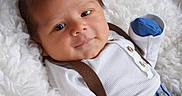 Sebastian joined the competition — help win amazing prizes! baby, infant, smile, face, clothing, suspenders, blue_pants, white_shirt, blanket, soft_texture, lying_down, cute, portrait, indoor, newborn, child, happy, closeup, skin, head