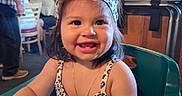 Layla joined the competition — help win amazing prizes! cheerful, child, clothing, cute, dress, face, hair, happy, headband, high_chair, indoor, necklace, people, person, portrait, restaurant, seated, smile, table, toddler