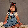 toddler, child, smiling, happy, sitting, denim_dress, minnie_mouse, hair_bow, red_bow, cute, indoors, floor_mat, playful, baby, portrait, clothing, person, face, feet, hand