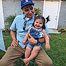 Layla is registered to the contest to win money with this photo: affection, blue_shirt, cap, casual_clothing, child, denim_overalls, door, family, garden, grass, happy, holding, man, outdoor, person, pigtails, sitting, smile, toddler, watch