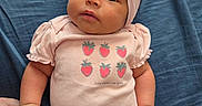 Layla joined the competition — help win amazing prizes! baby, infant, pink_clothing, headband, bow, strawberry_print, hand_holding, blue_blanket, cute, portrait, child, newborn, soft_fabric, lying_down, curious_expression, skin, face, person, indoor, toddler