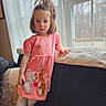 child, girl, pink_dress, rabbit_design, window, curtains, couch, pillow, indoors, natural_light, long_hair, white_tights, brown_boots, leaning, portrait, home, furniture, expression, casual, daylight