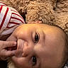 baby, blanket, child, close_up, cuddly, cute, face, fingers, hand, happy, indoors, infant, lying_down, playful, portrait, skin, smiling, soft_texture, striped_clothing, young