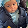 baby, baby_seat, blue_clothing, child, closeup, colorful_toy, cute, expression, face, hoodie, indoor, infant, person, portrait, seat, star_pattern, toy, vest, warm_clothing, young_child