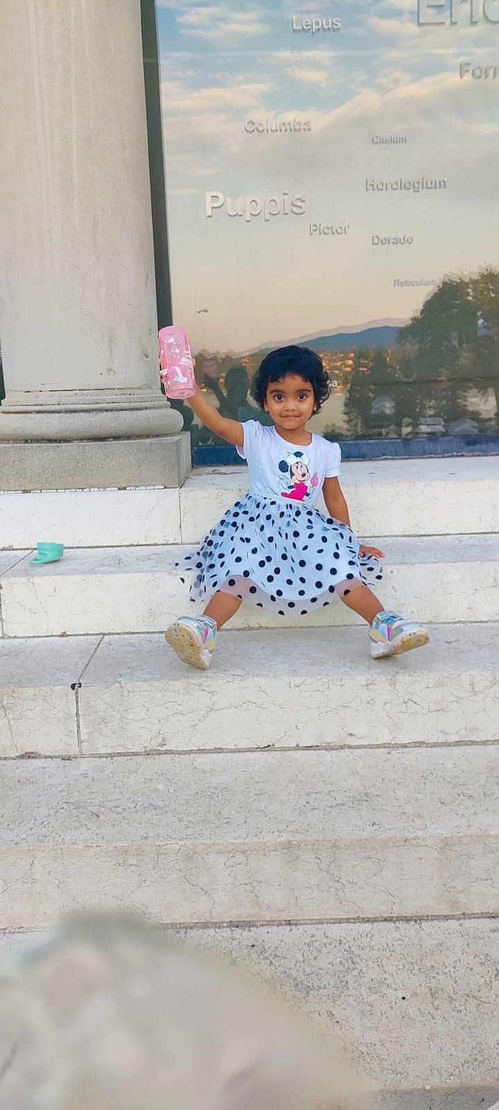 Priya Bhattacharya participe au concours pour gagner de l'argent avec cette photo : child, toddler, girl, polka_dot_skirt, minnie_mouse, tshirt, sneakers, pink_bottle, steps, marble, outdoor, reflection, glass_window, smiling, sitting, curly_hair, playful, casual_clothing, daylight, urban