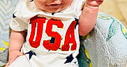 Rayan joined the competition — help win amazing prizes! baby, child, closeup, clothing, comfortable, cute, floor_tiles, indoor, infant, patterned_chair, person, portrait, raising_hand, sitting, smiling, soft_toy_chair, stars, usa, white_outfit, young