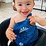 Zaid joined the competition — help win amazing prizes! toddler, child, smiling, blue_overall, dinosaur_print, high_chair, messy_face, indoor, tile_floor, couch, table, happy, cute, short_hair, baby, playful, person, home, furniture, casual