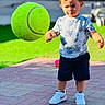 Zaid is registered to the contest to win money with this photo: toddler, child, tennis_ball, outdoor, grass, pavement, white_shoes, shorts, tshirt, sunlight, shadow, playing, concentration, curious, young_child, summer, daytime, sidewalk, background_blur, casual_clothing