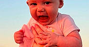Riley is registered to the contest to win money with this photo: baby, infant, child, portrait, pink, bow, headband, dress, clothing, smiling, open_mouth, facial_expression, sitting, outdoor, sky, pastel, warm_lighting, close_up, fashion, cute