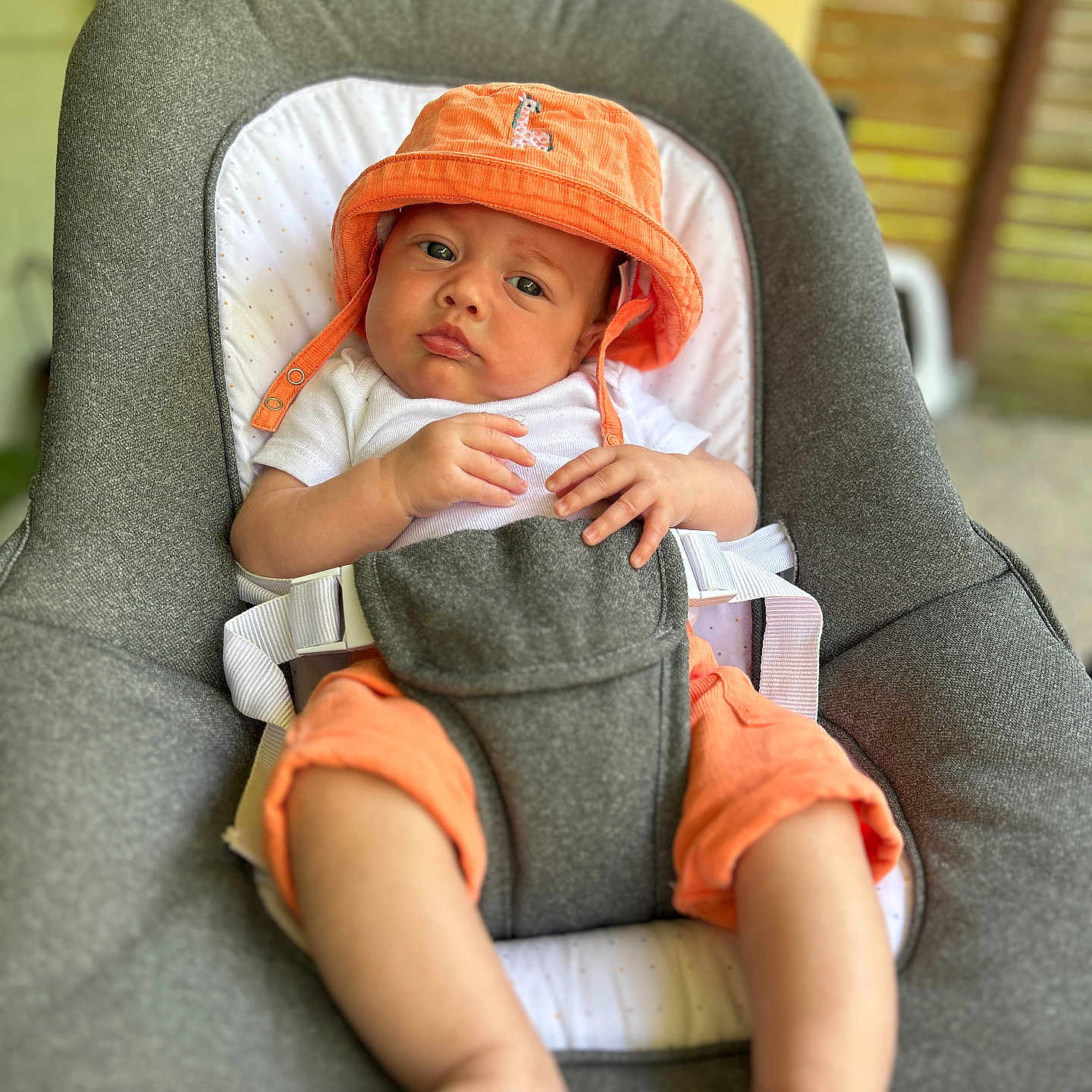Elio participe au concours pour gagner de l'argent avec cette photo : baby, baby_boy, baby_face, baby_feet, baby_hands, baby_seat, casual_clothing, child, comfortable, cute, gray_cushion, indoors, infant, orange_hat, orange_shorts, portrait, pouty_expression, relaxed, seated, white_shirt