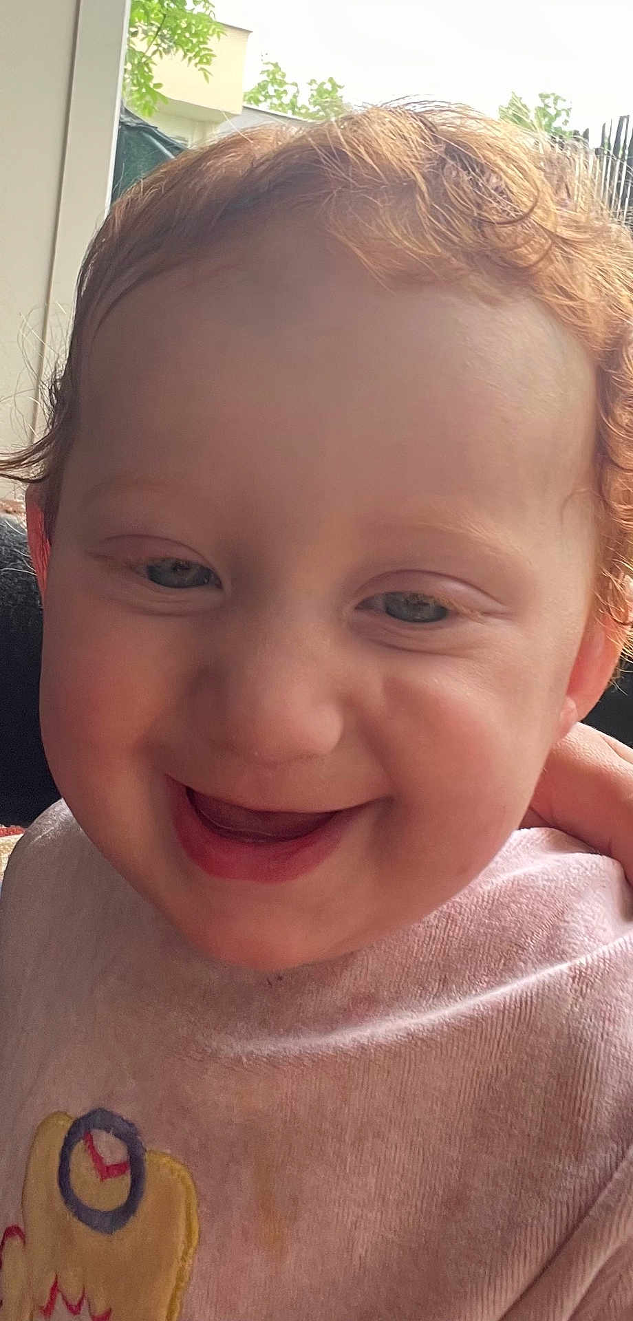 Sabriya a rejoint le concours — aidez-le/la à gagner de superbes lots ! bib, cheeks, child, close_up, clothing, curly_hair, cute, face, happy, indoors, joyful, natural_light, person, pink, portrait, red_hair, smile, toddler, window, young_child