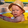 toddler, child, hat, inflatable_pool, yellow, water, pool, summer, sunlight, outdoor, swimming, float, baby, expression, face, arm, skin, toy, daylight, recreation