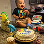 toddler, birthday, cake, cupcake, toy, kitchen, counter, smiling, child, celebration, candle, clothing, furniture, indoor, food, person, happy, toy_laptop, cup, lighting