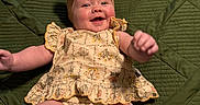 Blakley joined the competition — help win amazing prizes! baby, infant, child, portrait, smiling, happy, lying_down, floral_outfit, dress, headband, bow, green_quilt, blanket, indoor, closeup, face, arms, legs, joyful, cozy