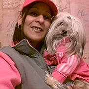 Tiffany is registered to the contest to win money with this photo: woman, dog, pet, pink_clothing, cap, vest, indoor, portrait, smile, long_hair, small_dog, furry, hand, holding, casual, fashion, adidas, cute, cozy, background_text