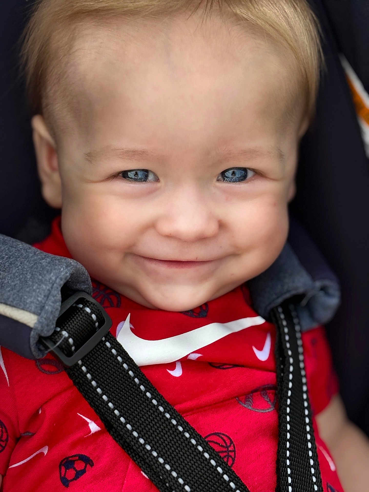 Waylon joined the competition — help win amazing prizes! baby, child, smiling, face, blue_eyes, red_shirt, sports_print, car_seat, harness, close_up, infant, cute, happy, portrait, straps, clothing, person, seatbelt, safety, young
