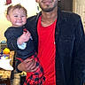 baby, child, adult, man, portrait, smiling, happy, indoors, family, holding, standing, black_clothing, red_shirt, plaid_outfit, kitchen, home, door, table, household, photography
