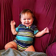 Sebastian is registered to the contest to win money with this photo: baby, child, smiling, sitting, portrait, indoor, couch, purple_couch, blanket, striped_outfit, onesie, happy, face, arms_raised, brown_hair, furniture, cozy, home, photography, infant