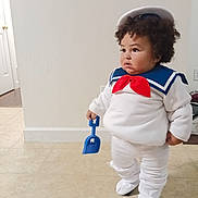 Draven joined the competition — help win amazing prizes! toddler, child, costume, sailor_outfit, hat, blue_collar, red_bow, plastic_shovel, indoor, floor, tile_floor, curly_hair, white_clothing, standing, person, cute, portrait, home, baby, expression