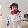 Draven joined the competition — help win amazing prizes! toddler, child, costume, sailor, hat, red_bow, blue_shovel, indoor, floor, curly_hair, white_outfit, toy, standing, cute, expression, person, clothing, play, young, floor_tile