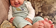 Ralph is registered to the contest to win money with this photo: baby, blanket, child, clothing, couch, cozy, cute, dinosaur, face, feet, happy, home, indoors, infant, person, pillow, portrait, sitting, smiling, toes