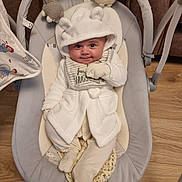 Ralph is registered to the contest to win money with this photo: baby, baby_bib, baby_rocker, child, clothing, cozy, cute, face, flooring, hood, indoor, infant, mittens, plush_toys, portrait, seated, smile, soft_toys, white_clothing, wood_floor