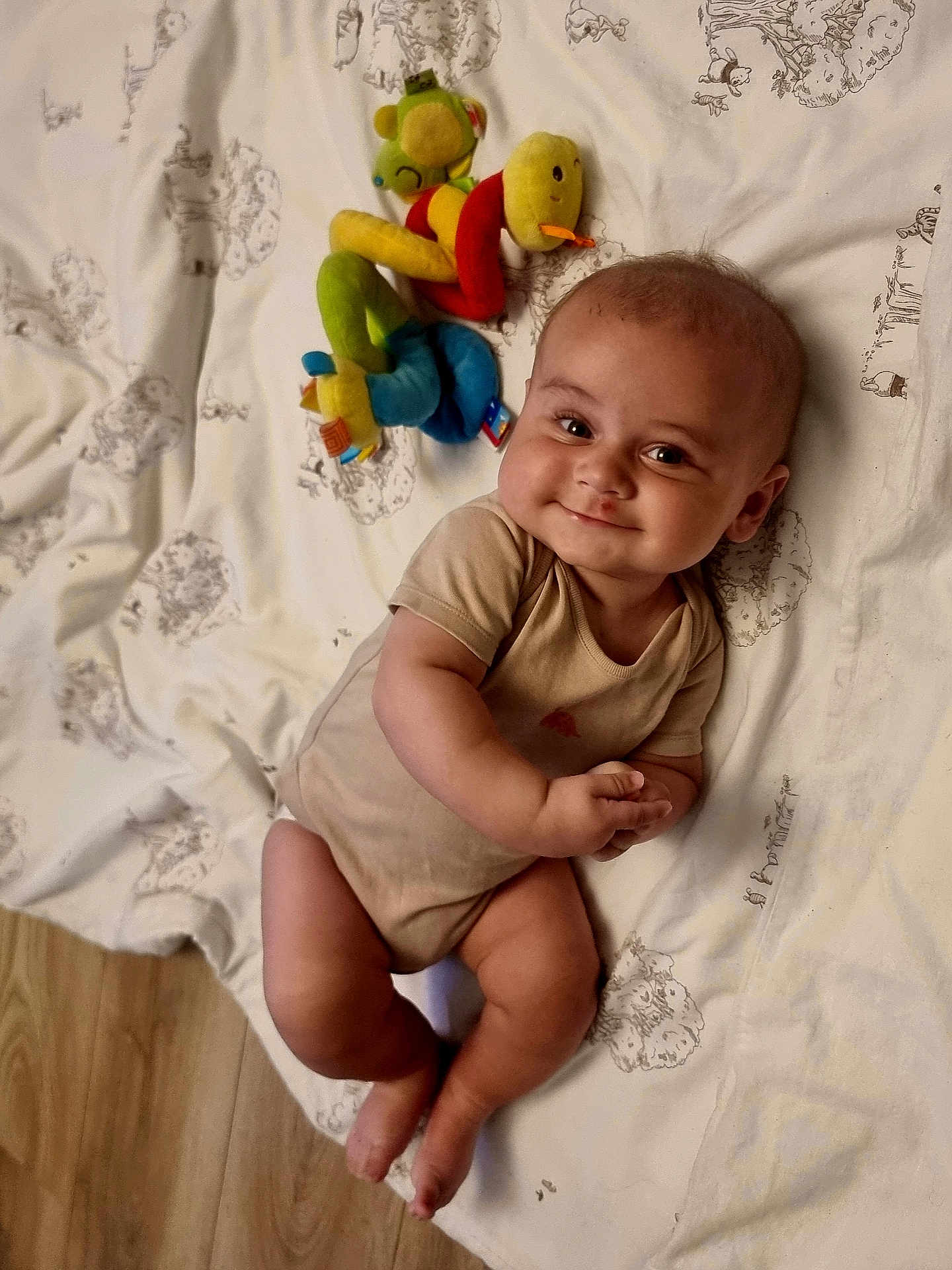 Ralph joined the competition — help win amazing prizes! baby, smiling, lying_down, plush_toy, blanket, floor, wooden_floor, infant, cute, child, indoors, soft_toy, colorful, one_person, happy, casual_clothing, face, skin, legs, hands