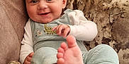 Ralph is registered to the contest to win money with this photo: baby, smiling, couch, pillow, feet, infant, clothing, indoor, happy, person, cute, child, relaxing, home, soft, cozy, face, sitting, blue_overall, white_shirt