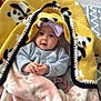 baby, blanket, panda_print, pink_blanket, hat, clothing, infant, portrait, indoor, cozy, cute, smile, hands, face, child, warm, soft, person, headwear, seated