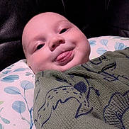 Teddy is registered to the contest to win money with this photo: baby, child, closeup, cozy, cute, expression, face, floral_pattern, green_clothing, happy, head, indoors, infant, lying_down, person, pillow, playful, skin, smile, tongue