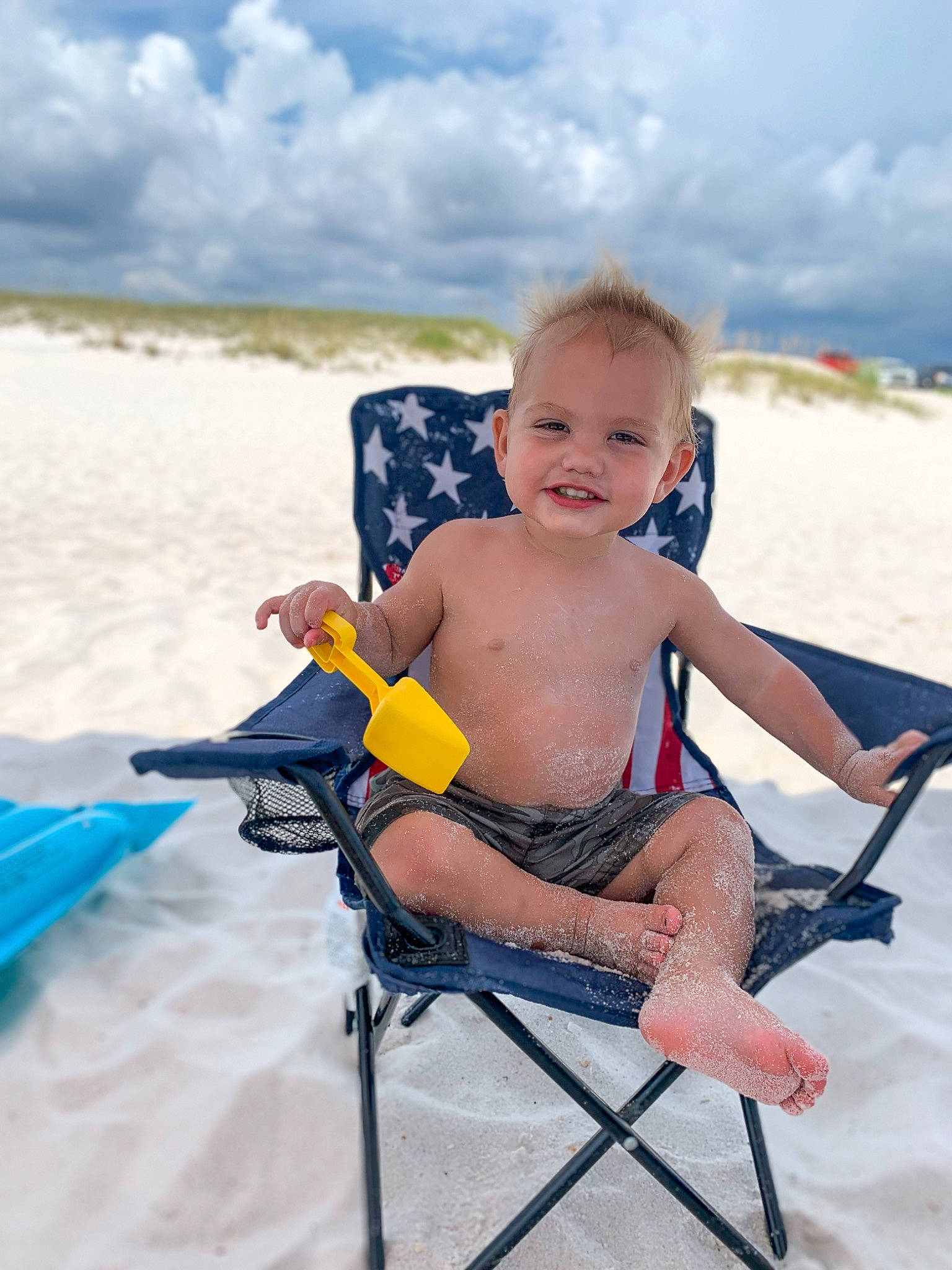 Chase is registered to the contest to win money with this photo: baby_toddler_clothing, barefoot, body_of_water, chair, child, cloud, folding_chair, fun, happy, joy, landscape, leisure, outdoor_furniture, people_on_beach, person, recreation, shorts, sitting, sky, smile