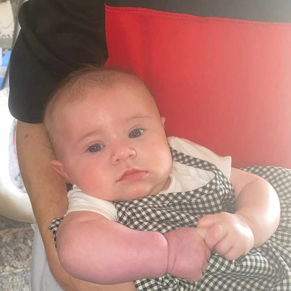 Iris is registered to the contest to win money with this photo: arm, baby, bodypart, clothing, cushion, dress, face, finger, hand, hat, head, homedecor, newborn, pants, person, photography, portrait, shirt, t_shirt, vest