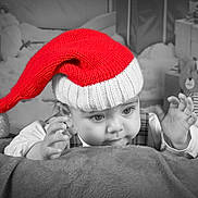 Isaac a rejoint le concours — aidez-le/la à gagner de superbes lots ! baby, santa_hat, blanket, teddy_bear, christmas, holiday, presents, festive, child, cute, black_and_white, red, knit_hat, smiling, portrait, indoors, soft_texture, decorations, holiday_season, young_child