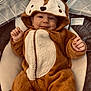 baby, infant, child, animal_costume, onesie, hood, deer_costume, smile, cute, cozy, plush, zipper, fingers, hands, eyes, bouncer, blanket, fabric, portrait, indoors