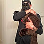 Grim is registered to the contest to win money with this photo: animal, black_cat, black_clothing, cat, door, floor, fluffy_cat, funny_pose, hand, head_covering, holding, indoor, long_tail, person, pet, portrait, real_photo, tattoo, wall, yellow_eyes