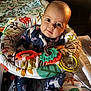 Arielle is registered to the contest to win money with this photo: baby, infant, child, face, eyes, head, clothing, onesie, baby_seat, toy, plastic_rings, patterned_fabric, blanket, indoor, portrait, cute, colorful, playful, seated, curious