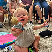 Hadley is registered to the contest to win money with this photo: toddler, child, dolls, toy_car, floor, people, indoor, smile, play, sitting, clothing, group, legs, hands, hair, face, happy, background, casual, gathering