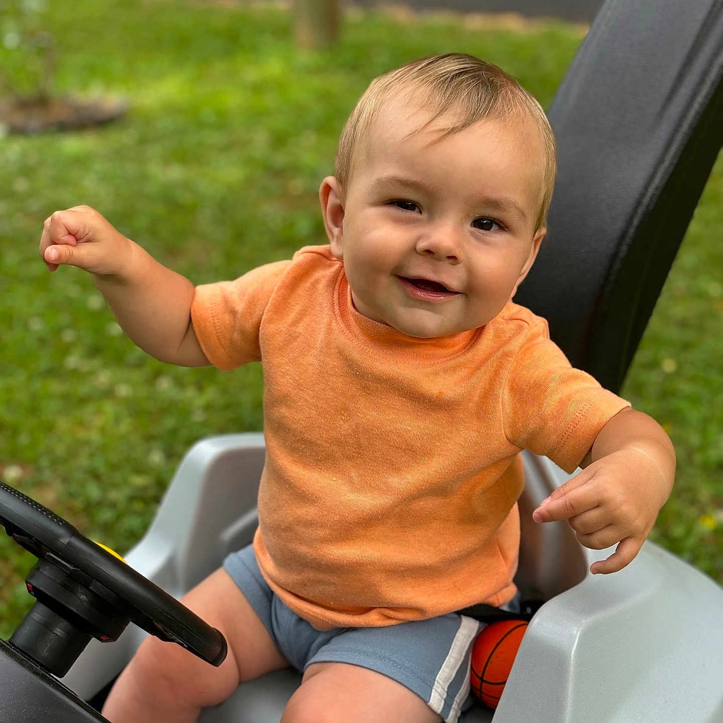 Bennett joined the competition — help win amazing prizes! baby, bodypart, clothing, face, finger, grass, hand, happy, head, machine, outdoors, person, photography, plant, portrait, shorts, sitting, summer, transportation, wheel