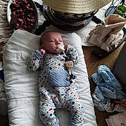 Sacha a rejoint le concours — aidez-le/la à gagner de superbes lots ! baby, infant, onesie, cushion, table, potpourri, hat, clothes, baby_wipes, wooden_table, toy, teething_toy, white_socks, patterned_clothing, indoor, floor, folded_clothes, household_items, relaxing, lying_down