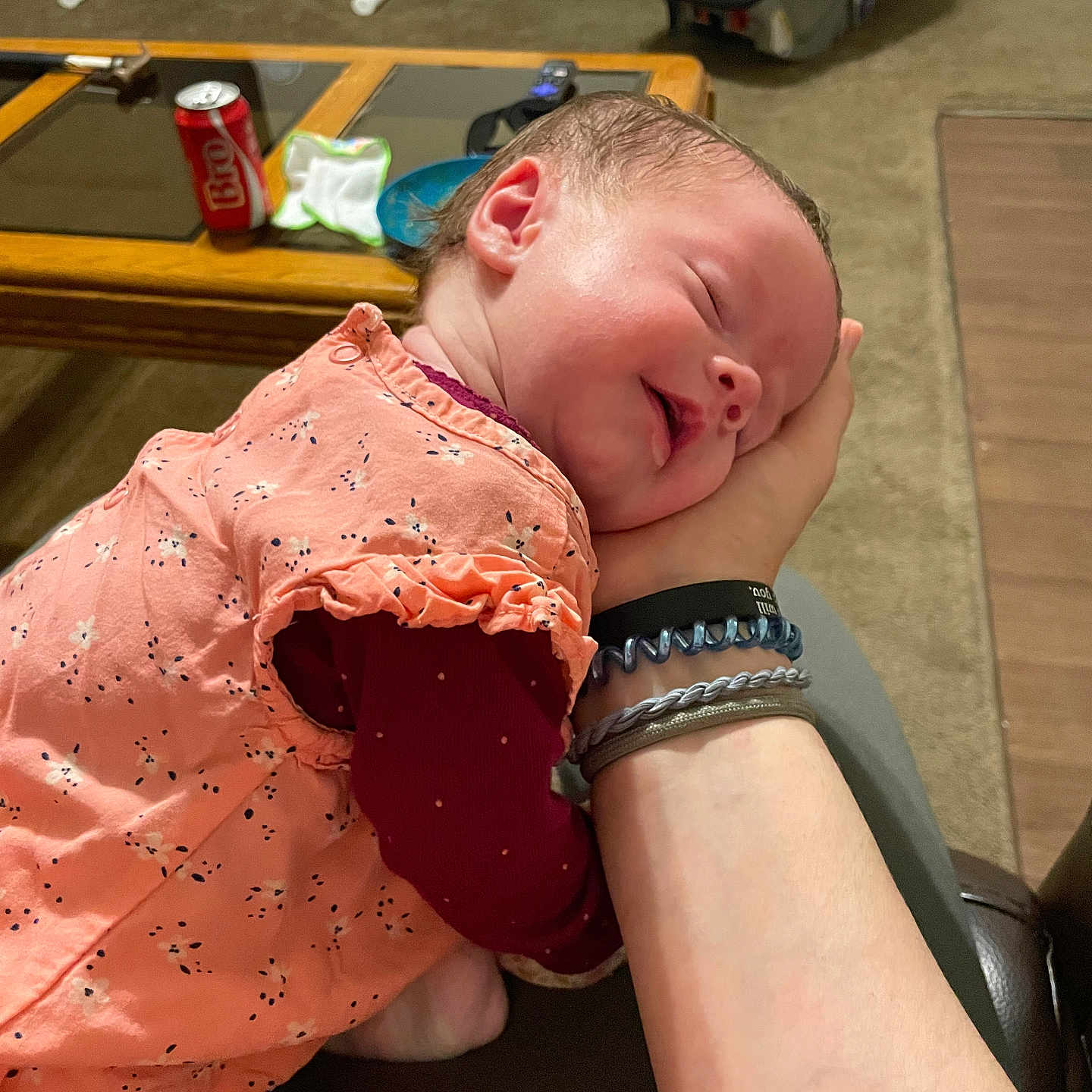 Amelia is registered to the contest to win money with this photo: baby, blanket, can, car_seat, carpet, child, coffee_table, face, hand, head, indoor, infant, living_room, maroon_sleeves, peaceful, peach_dress, person, sleep, sleeping, soft_lighting