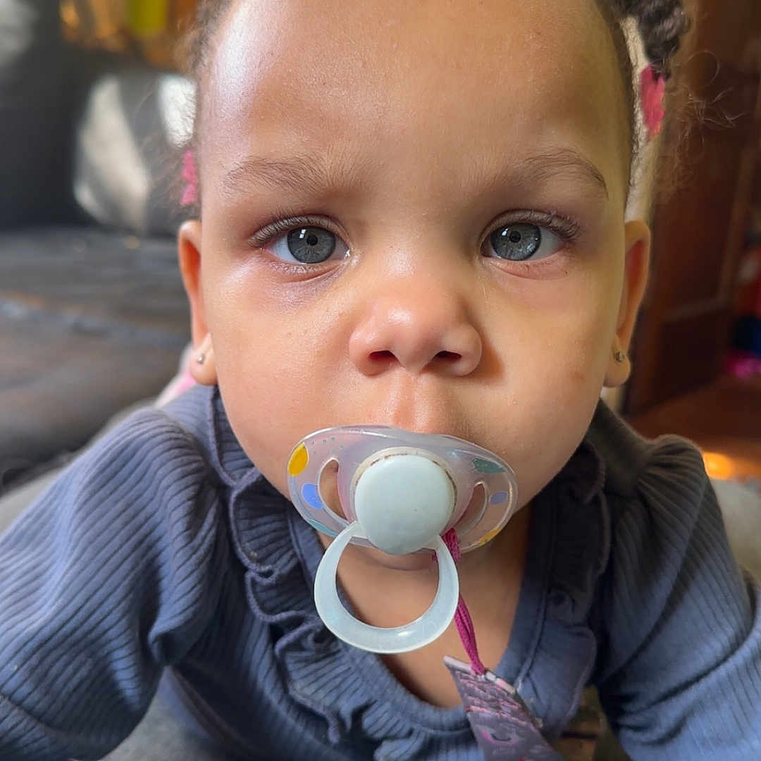 Treasure joined the competition — help win amazing prizes! baby, blue_eyes, child, closeup, clothing, couch, cute, earrings, expression, face, furniture, hair, home, indoor, pacifier, person, portrait, sitting, toddler, young_child