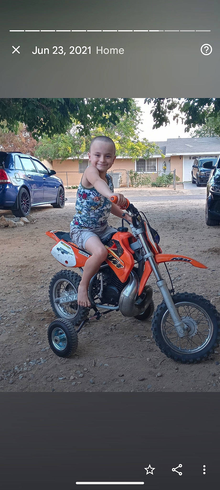 Ayden is registered to the contest to win money with this photo: automotive_design, automotive_lighting, automotive_tire, car, fender, joy, land_vehicle, landscape, motor_vehicle, motorcycle, person, rim, shorts, smile, spoke, synthetic_rubber, t_shirt, tire, tread, tree