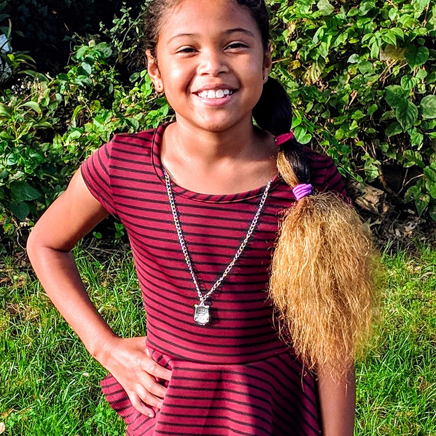 Yasmin is registered to the contest to win money with this photo: abdomen, child, child_model, clothing, emotion, facial_expression, fun, garden, girl, grass, grass_family, happiness, joy, long_hair, pattern, person, pink, plant, smile, tree