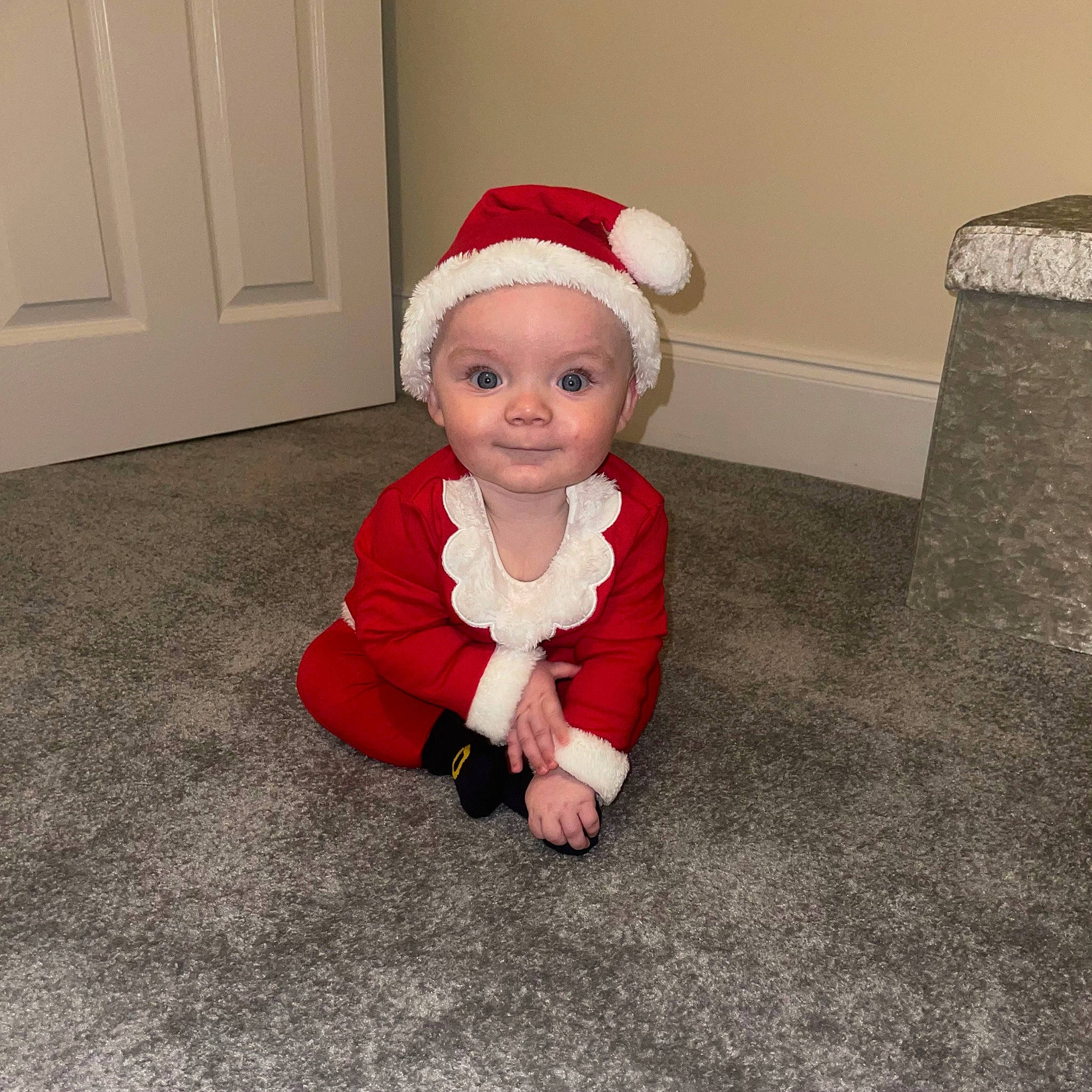 Louie joined the competition — help win amazing prizes! baby, baby_toddler_clothing, carmine, carpet, child, costume_hat, door, face, floor, flooring, fun, hat, human_body, person, road_surface, room, sitting, sleeve, smile, toddler