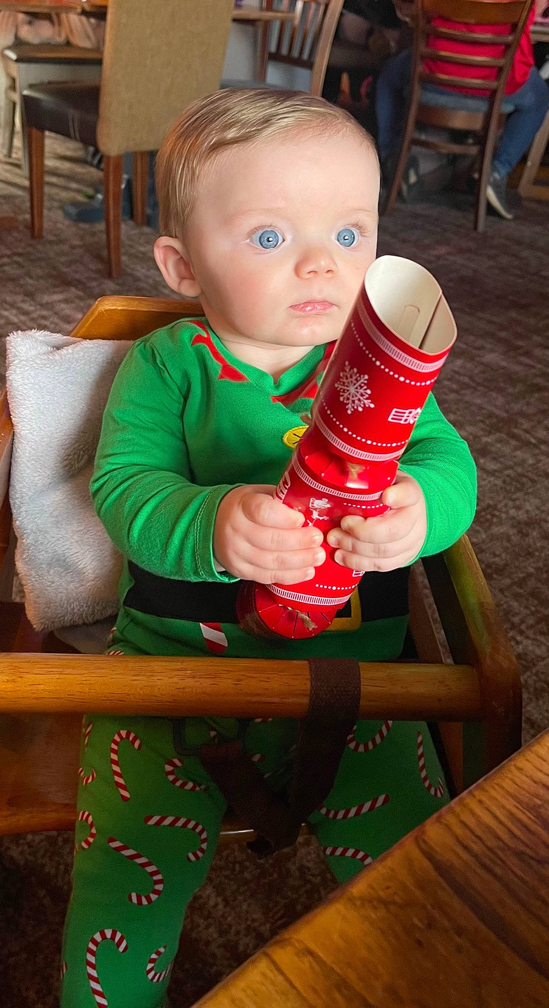 Louie is registered to the contest to win money with this photo: baby, baby_toddler_clothing, chair, child, christmas, christmas_eve, drinking, drinkware, event, fictional_character, fun, green, hardwood, holiday, person, plastic_bottle, play, room, sitting, toddler