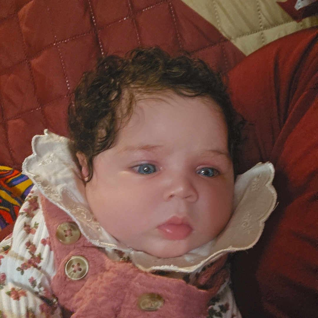 Melvina is registered to the contest to win money with this photo: applique, baby, bodypart, bonnet, clothing, coat, couch, cushion, face, furniture, hat, head, homedecor, hood, jacket, pattern, person, photography, portrait, sitting