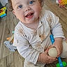 baby, child, smiling, blue_eyes, toy, indoor, wooden_floor, sitting, cute, happy, infant, clothing, sock, playtime, face, person, floor, holding, young_child, casual